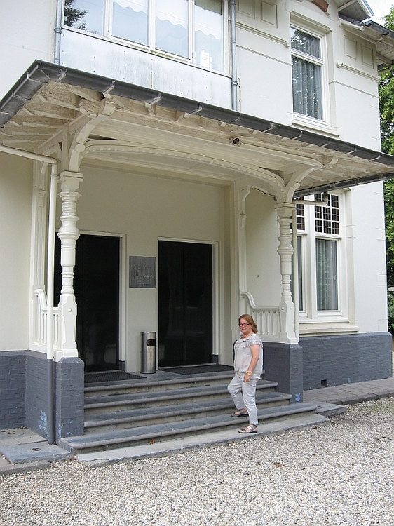 Rietje de Jong voor de ingang van de aula van Vredenhof aan de Haarlemmerweg Bron: foto José Stolp, 2014 