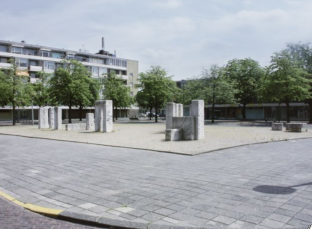 De beelden toen ze nog op het Confuciusplein stonden, links de achterkant van de huizen aan de Senecastraat, rechts de schaduw van de elektrische klok wie, wat, wanneer, waar Foto: Beeldbank van het Stadsarchief van de gemeente Amsterdam, fotograaf Martin Alberts, 7 juli 2003 